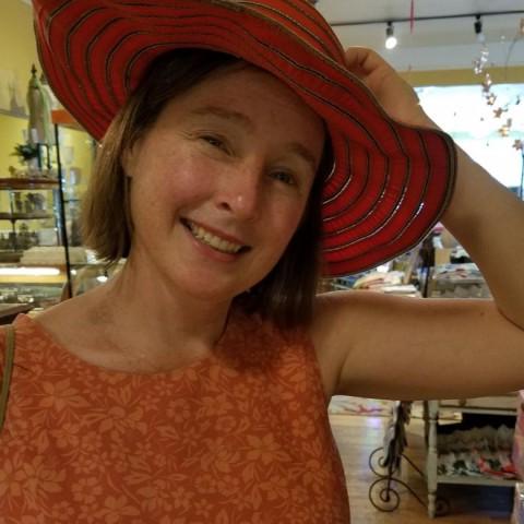 Susan McHugh poses wearing a red hat